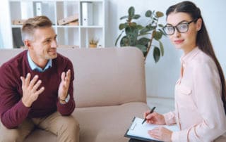 Addiction counselor listening and taking notes from a client.