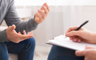 Psychotherapist writing notes, assessing patient's health and giving diagnosis to man sitting on couch during counseling session