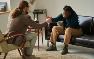 substance abuse counselor and a girl in depression sitting on sofa and crying while counselor giving glass of water